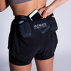 Woman wearing Ultimate Direction Women's Hydro Short, putting phone into center pocket
