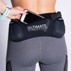 Woman wearing Ultimate Direction Women's Hydro 3/4 Tight, putting phone into center pocket