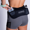 Woman wearing Ultimate Direction Women's Hydro Skin Short, putting water bottle into side pocket